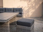 Close-up of the Atrico Lounge Set wicker stool with grey cushion beside the coffee table